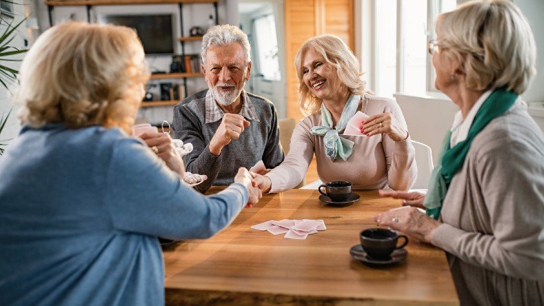 Senior friends play cards at home.